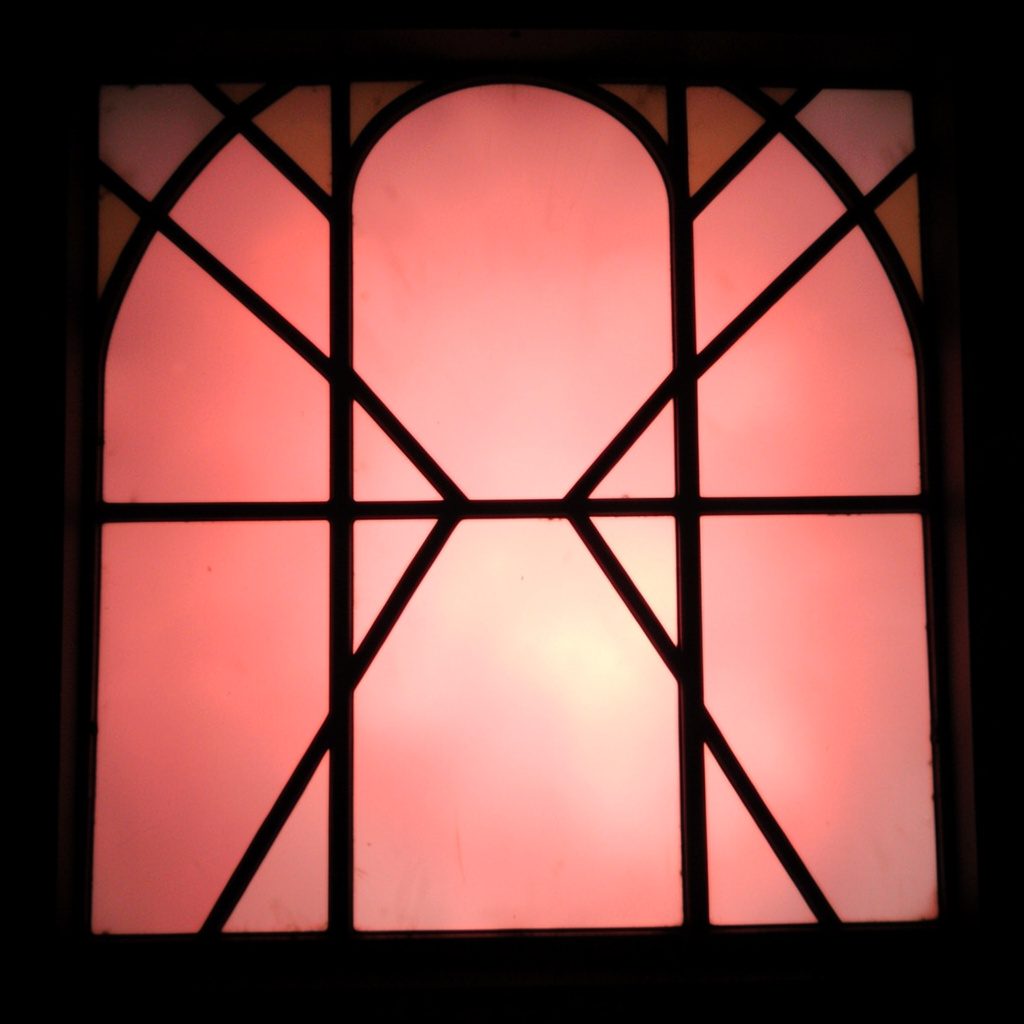 Stained-glass panel with bold dark outlines, deep purple and soft pink segments, contemplative and artistic mood