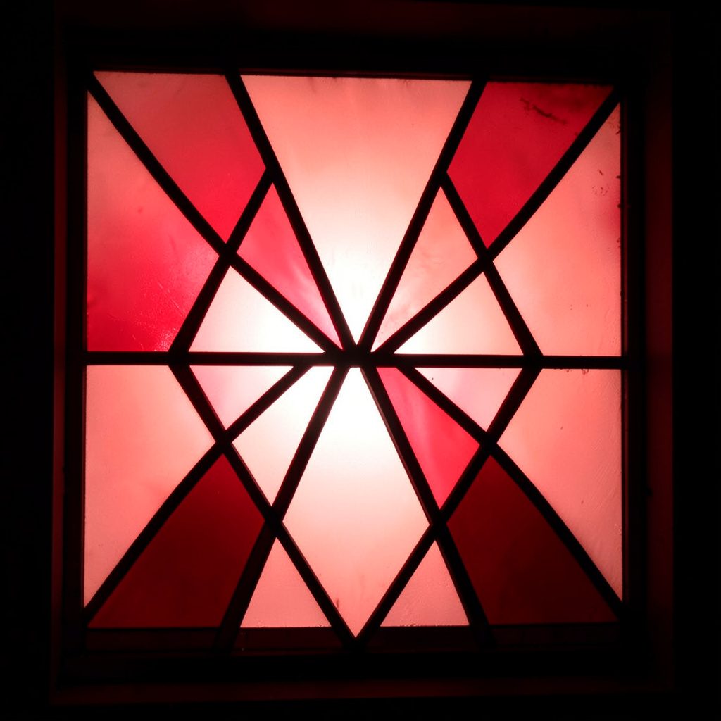 Stained-glass composition with bold leaded segments in dusty pink, soft turquoise, and pale gold, serene and warm