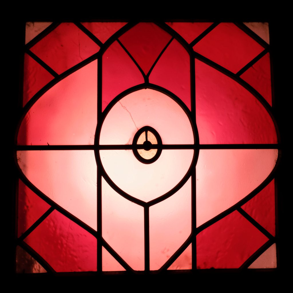 Stained-glass composition with bold leaded segments in rose, turquoise, and soft pink tones, luminous and warm